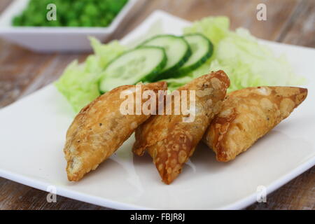 Samosas indiens avec salade verte sur plaque blanche, gros plan Banque D'Images