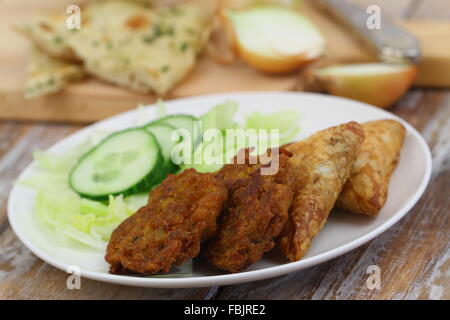 Des collations indiennes dont l'oignon bhajis et samossas, et salade verte Banque D'Images