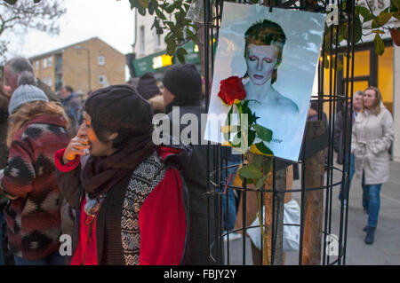 Brixton, Londres, Royaume-Uni. 17 janvier 2016. Sous la fresque de fleurs David Bowie en face de la station de métro de Brixton continuent de croître d'une semaine après sa mort. Les messages écrits sur l'affiche dans le magasin à Morley en référence son épouse Amin's cosmetics à côté de la fresque sont devenus populaires. Credit : JOHNNY ARMSTEAD/Alamy Live News Banque D'Images