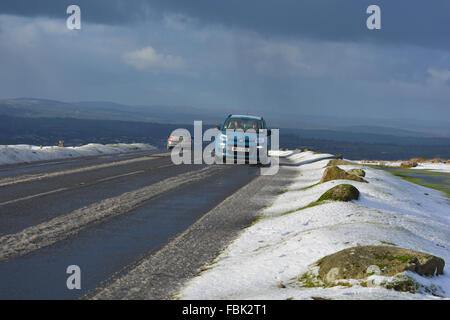 Voitures sur la colline de porc, une route dans le parc national du Dartmoor, en hiver. Conditions de conduite dangereuses avec la neige et la glace. Banque D'Images