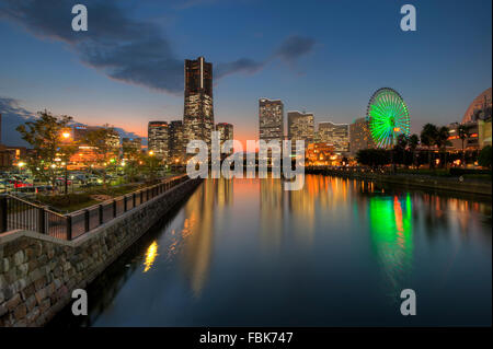 La réflexion de Yokohama Landmark Tower et les immeubles de bureaux modernes sur l'eau au cours de la fin de soirée Banque D'Images