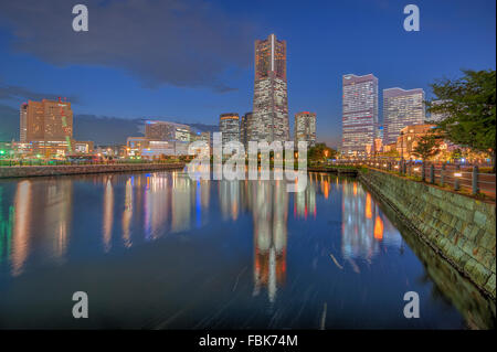 La réflexion de Yokohama Landmark Tower et les immeubles de bureaux modernes sur l'eau au cours de la fin de soirée Banque D'Images