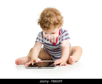 Kid boy using tablet, assis sur le plancher Banque D'Images