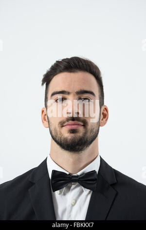 Close up portrait of young man with head in tuxedo se pencha en arrière avec Bow Tie. Portrait sur fond gris studio Banque D'Images