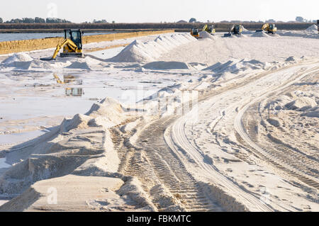 Italie, Sicile, Trapani. Une pelle sur chenilles Komatsu la récolte du sel de mer à partir d'un bassin d'évaporation. Banque D'Images