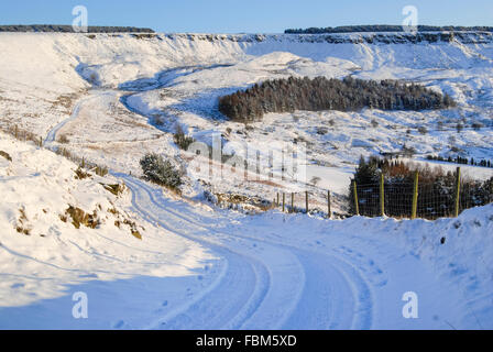 Une ferme piste menant à travers un paysage vallonné et de neige dans le Nord de l'Angleterre. Voir à bord près de Coombes, Glossop Derbyshire. Banque D'Images