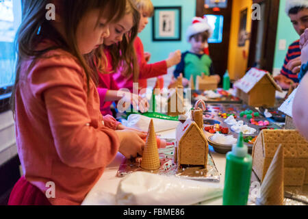 Les enfants décorer maisons en pain d'épices avec bonbons et de givre Banque D'Images