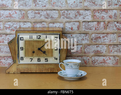 Vintage art deco pendule en bois avec l'effet de mur en briques anciennes et fond chine tasse et rempli de plateau Banque D'Images