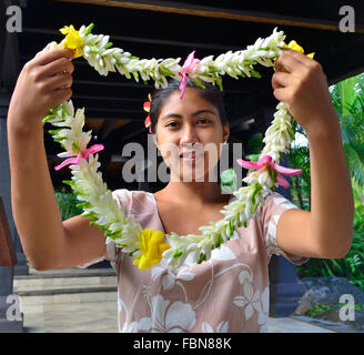 Belle fille de l'île Cook tenant un collier traditionnel de fleurs ou Lei comme un salut sur l'île du Pacifique Sud d'Aitutaki, îles Cook Banque D'Images