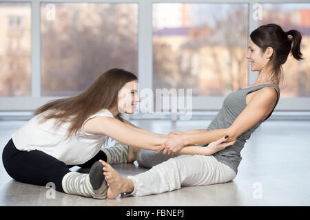 Fitness, stretching, la pratique de groupe de deux beaux happy fit jeunes travaillant à l'aide de l'instructeur, club de sport Banque D'Images