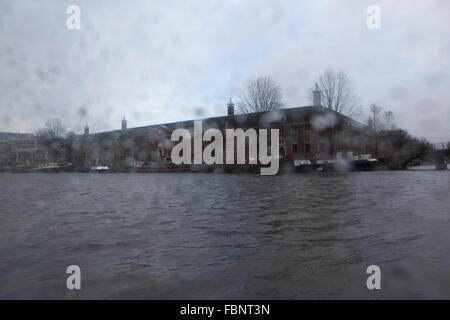 Gouttes de pluie sur une fenêtre au centre d'Amsterdam, aux Pays-Bas. L'Hermitage Amsterdam est vu au-delà de l'eau. Banque D'Images