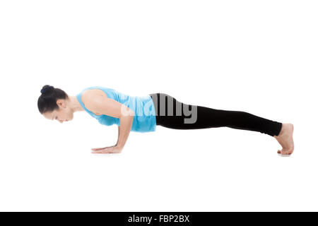 Yogi sportive girl faire des exercices de yoga, push-ups, posent Chaturanga Dandasana (Four-Limbed posent le personnel), isolé Banque D'Images