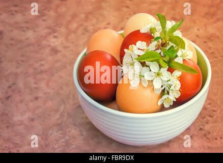 Sur la table dans un vase en céramique sont les oeufs de Pâques peints et un petit bouquet de fleurs de poires. Banque D'Images