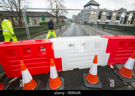 Storm Desmond a donné lieu à plus d'une trentaine de ponts détruits ou endommagés en Cumbria, perturbant les transports. Dans Kendal pont Victoria, qui avait été ouverte, est maintenant fermé à la circulation et les piétons après avoir découvert les plongeurs que les fondations sous ses jambes avaient été complètement minée. La fermeture a provoqué le chaos dans la circulation comme le pont de Kendal est le carrefour principal dans le nord de la ville sur la rivière Kent. Cette photo montre les travailleurs du Conseil mettant les obstacles jusqu'à arrêter tout passage à niveau. Photo prise le 14 janvier 2015. Banque D'Images