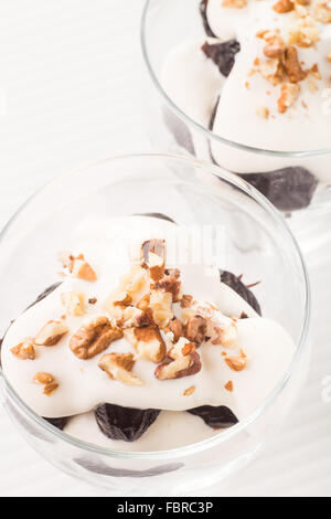 Dessert aux pruneaux, noix et crème fouettée dans verre bowles sur la table Banque D'Images