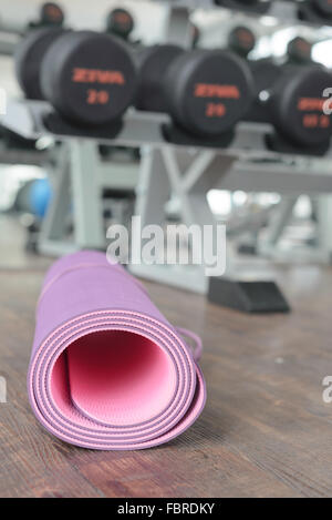 Close up de tapis de yoga roulé sur un parquet dans une salle de sport. Banque D'Images