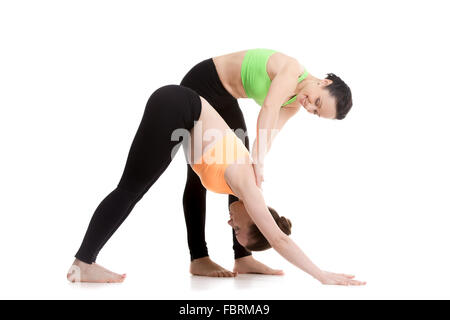 Deux belles filles sportive pratiquer le yoga avec partenaire, étudiant aide instructeur, stretching en chien orientée vers le yoga pose Banque D'Images