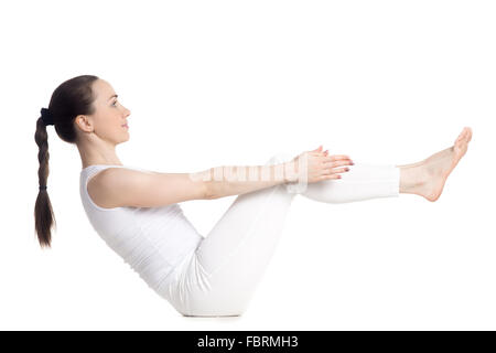 Belle sportive souriante jeune femme en blanc sportswear faisant des exercices pour le dos, les jambes et l'apa, assis dans Paripurna navasana Banque D'Images