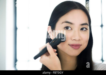 Woman applying blush Banque D'Images