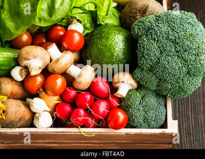 Les légumes bio frais dans des caisses en bois avec de la salade,les carottes,les champignons,tomates,brocolis,avocat,radis, les oignons et l'ail Banque D'Images