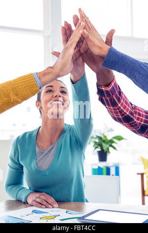 Femme d'affaires faisant équipe avec high five in creative office Banque D'Images