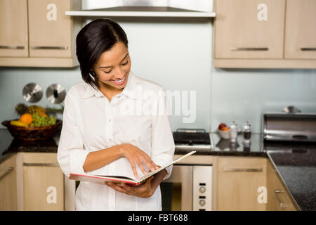 Smiling brunette reading book Banque D'Images