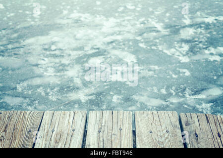 Ancienne jetée en bois aux couleurs rétro sur la glace, résumé fond avec l'espace pour le texte. Banque D'Images