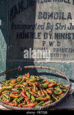 Assortiment de rouge, orange et vert piments séchant au soleil dans la rue à Bomdila, Inde. Banque D'Images