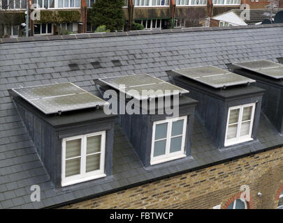 Les panneaux solaires sur les toits de lucarne, Brentford, Londres, Royaume-Uni. Dans le besoin de nettoyage. Banque D'Images