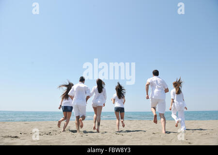 Groupe des gens heureux s'amuser et courir sur la plage Banque D'Images