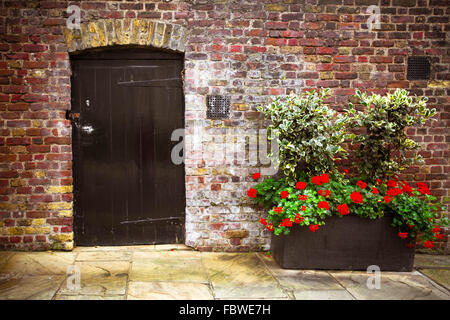 Charmante maison en brique avec l'extérieur, des fleurs et des panneaux de porte Banque D'Images