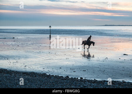 Ferryside, Carmarthenshire, Pays de Galles, Royaume-Uni. 19 janvier, 2016. Après des jours de pluie sur une journée ensoleillée au coucher du soleil/coucher du soleil.Si amèrement froid un jockey son cheval galope sur la plage vide à Ferryside, Carmarthenshire, Pays de Galles, Royaume-Uni Crédit : Paul Quayle/Alamy Live News Banque D'Images