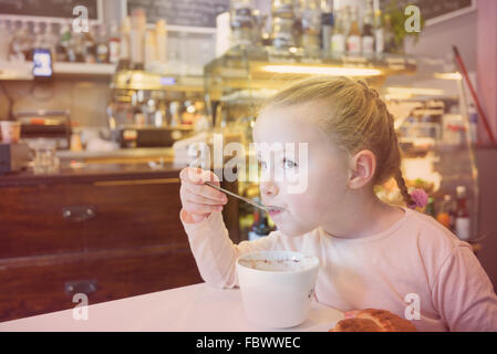 Belle jeune fille au bar pour le petit déjeuner. Banque D'Images