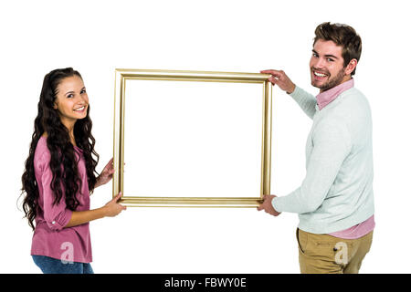 Smiling couple holding photo frame Banque D'Images