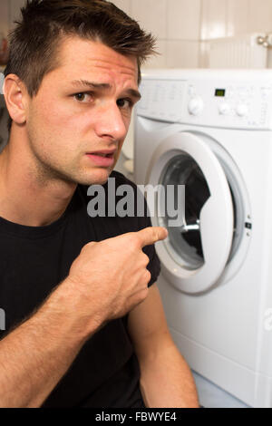 Jeune homme malheureux avec lave linge Banque D'Images