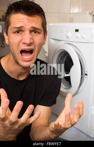 Jeune homme malheureux avec lave linge Banque D'Images