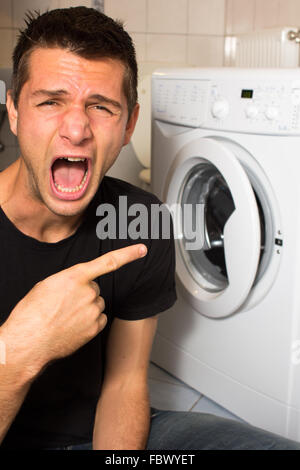 Jeune homme malheureux avec lave linge Banque D'Images