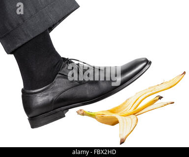 Jambe mâle dans la bonne chaussure noire glisse sur une peau de banane isolé sur fond blanc Banque D'Images