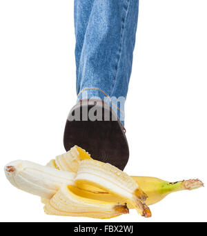 Pied gauche mâle en jeans et Brown Shoe stepping on banana isolé sur fond blanc Banque D'Images