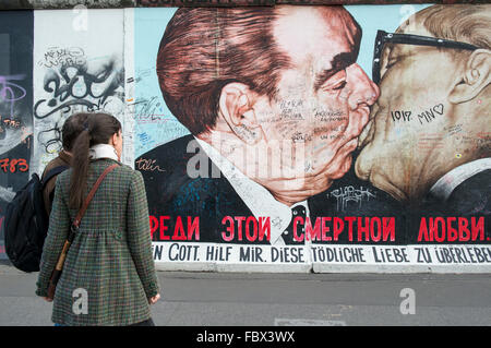 Les touristes de l'oeuvre d'affichage sur le mur de Berlin à l'East Side Gallery représentant un baiser entre Leonid Brejnev et Erich Honecker Banque D'Images