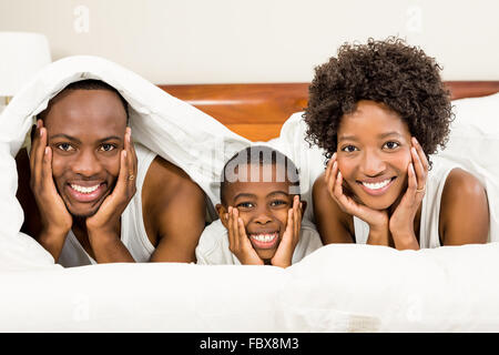 Happy Family posing in bed sous couverture Banque D'Images