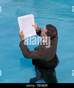 Senior man holding document prêt hypothécaire dans l'eau Banque D'Images