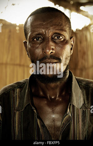 Homme barbu loin à l'intérieur d'une maison à Dodom, région Afar, Ethiopie, la dépression Danakil Banque D'Images