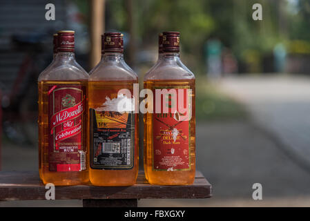 Les bouteilles d'alcool minable qui ont été remplies avec de l'essence pour la vente. Sur un banc à l'extérieur du marché du samedi, Balipara Assam, Inde. Banque D'Images