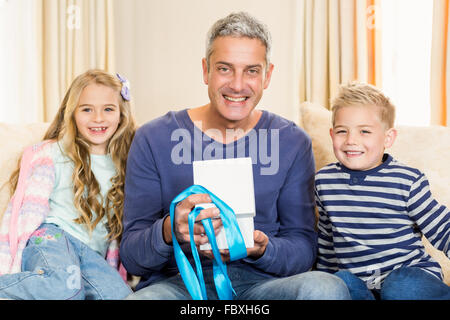 Ouverture père cadeau fait par les enfants sur canapé Banque D'Images