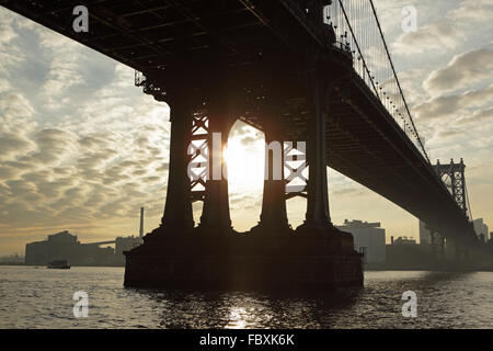 Lever du soleil sous le pont de Manhattan s'étendant sur l'East River en vue de Brooklyn industriel Banque D'Images