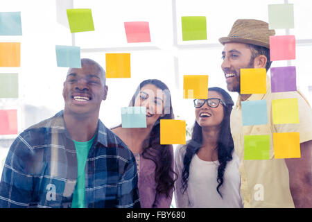 Smiling business people standing in front of adhesive notes Banque D'Images