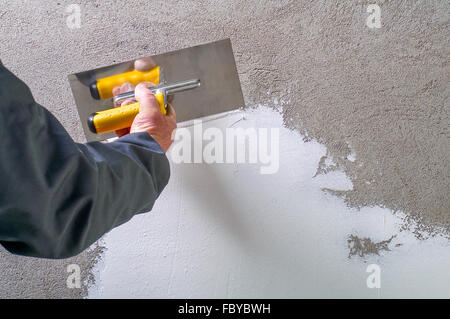 Travailleur de la construction - Plâtrage et lissage mur de béton avec du ciment blanc par une truelle d'acier - spatule aligne Banque D'Images