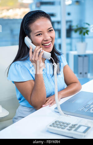 Smiling businesswoman using landline Banque D'Images