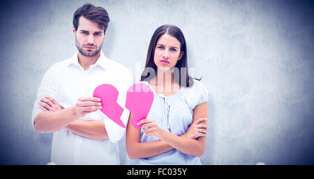 Image composite de colère couple holding deux moitiés de cœur brisé Banque D'Images